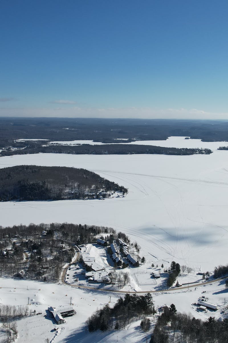 A stunning aerial view of a frozen landscape in Huntsville, Ontario, featuring snow-covered forests and icy lakes.
